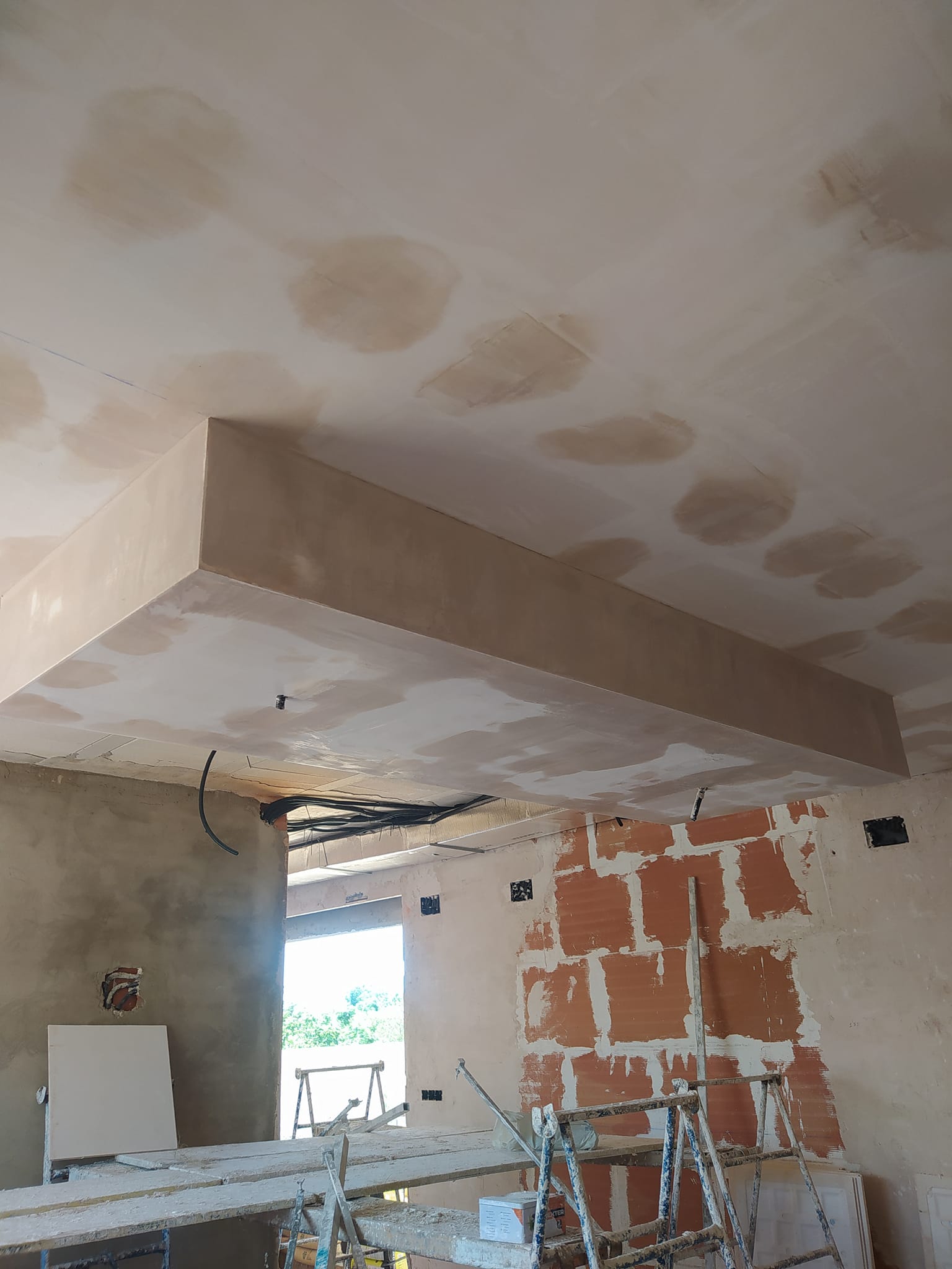 Escayolista preparando moldura en techo con andamio